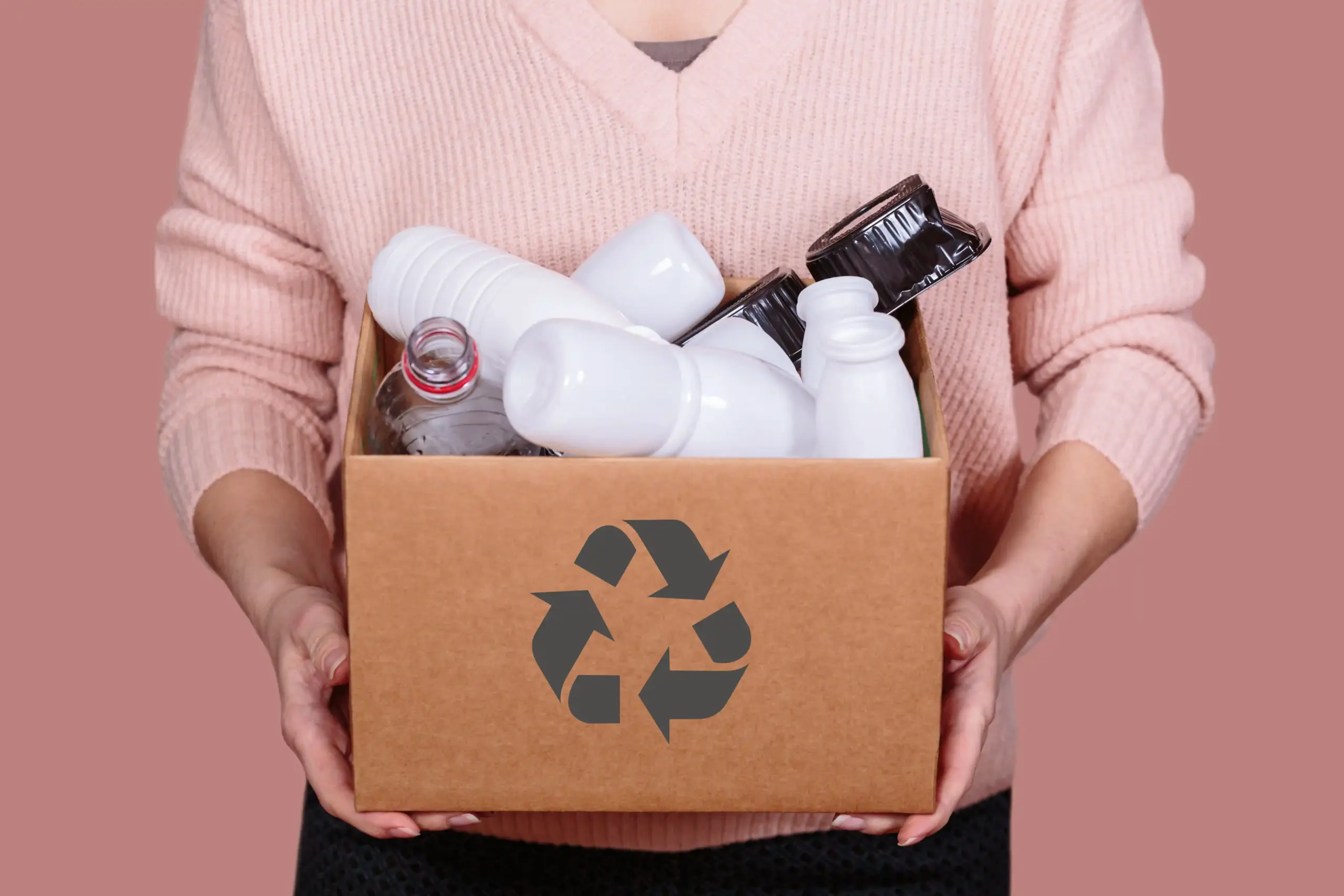 Frau hält Karton mit recyclebaren Kunststoffteilen
