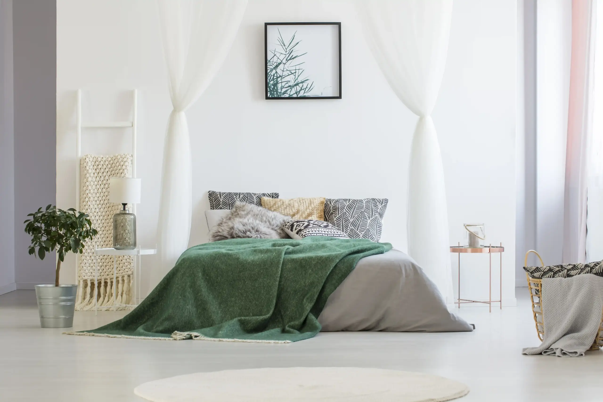 Gemütliches Schlafzimmer mit grünem Überwurf, Kissen und Tageslicht