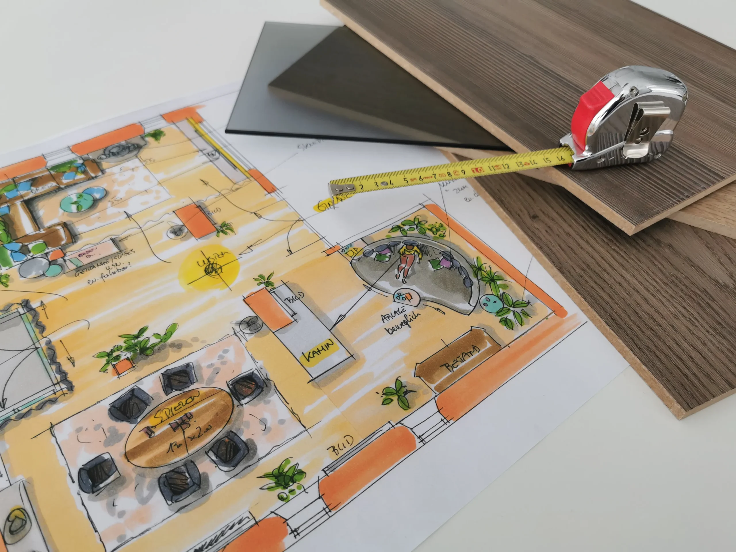 Grundriss-Skizze auf Papier neben Maßband, helles Wohnzimmer im Hintergrund